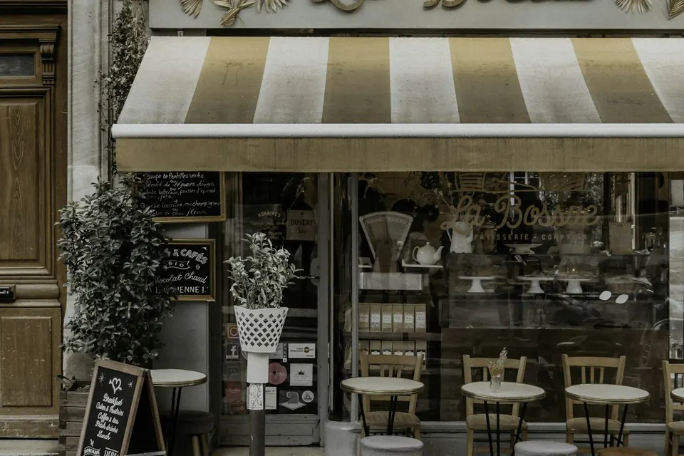 Devanture d'une boulangerie française avec un auvent rayé et une petite terrasse