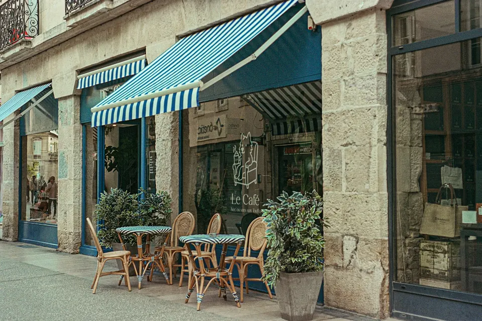 Terrasse de restaurant avec des auvents rayés bleus, des tables et des chaises en rotin